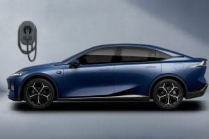 Blue electric car parked indoors, plugged into a wall charger for charging.
