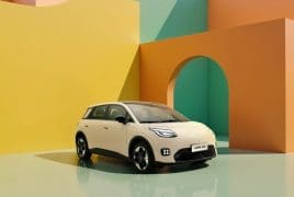 White compact SUV parked in a vibrant geometric studio backdrop with yellow, orange, teal walls and an arched opening behind it.
