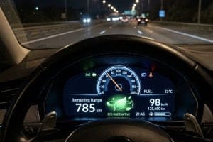 Car dashboard at night showing eco mode, 785 km remaining range, and speed 98 km/h on a highway.