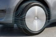 Close-up of a car wheel with a silver aerodynamic hubcap and blue airflow lines illustrating reduced air resistance around the tire.