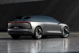 Rear three-quarter view of a silver futuristic concept car on a reflective tile surface with seamless design.