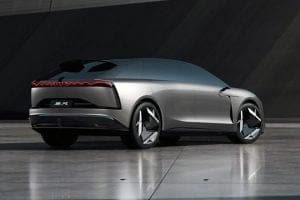 Rear three-quarter view of a silver futuristic concept car on a reflective tile surface with seamless design.