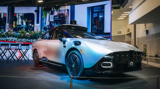 Img3222 | ยางรถยนต์ ราคาอัปเดต 2026 ครบทุกยี่ห้อ รวมยาง Ev | Autotirechecking Electric sports coupe on display in a showroom with a large LED wall behind and a row of chairs nearby, spotlighting its sleek lines.