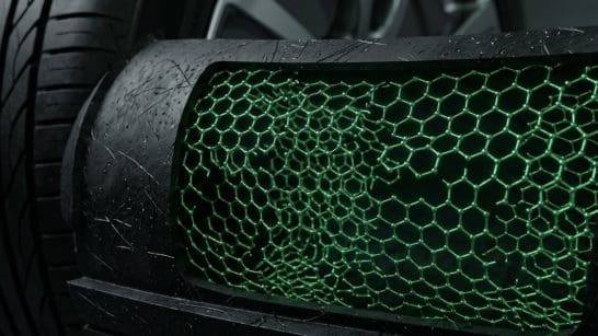Img3345 | ยางรถยนต์ ราคาอัปเดต 2026 ครบทุกยี่ห้อ รวมยาง Ev | Autotirechecking Close-up of a car's front grille with a green honeycomb mesh and a tire in the background, focusing on texture.