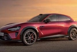 Red sports SUV parked on a paved surface at sunset, showing its sleek lines and large black alloy wheels.