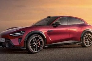 Red sports SUV parked on a paved surface at sunset, showing its sleek lines and large black alloy wheels.