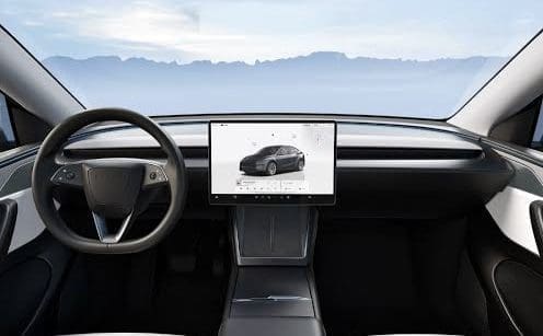 Img3395 | ยางรถยนต์ ราคาอัปเดต 2026 ครบทุกยี่ห้อ รวมยาง Ev | Autotirechecking Front-seat view of a modern car interior with a large central touchscreen displaying a car image, a round steering wheel, and a mountain landscape visible through the windshield.