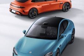 Two sports cars seen from above: a blue sedan in front and an orange SUV behind, on a light surface.