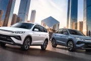 Two BYD SUVs parked in a modern city plaza, white and blue models with glass skyscrapers in the background.