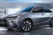 Front three-quarter view of a silver Toyota Yaris Ativ HEV Premium sedan in a modern concrete setting with sleek lines and alloy wheels.